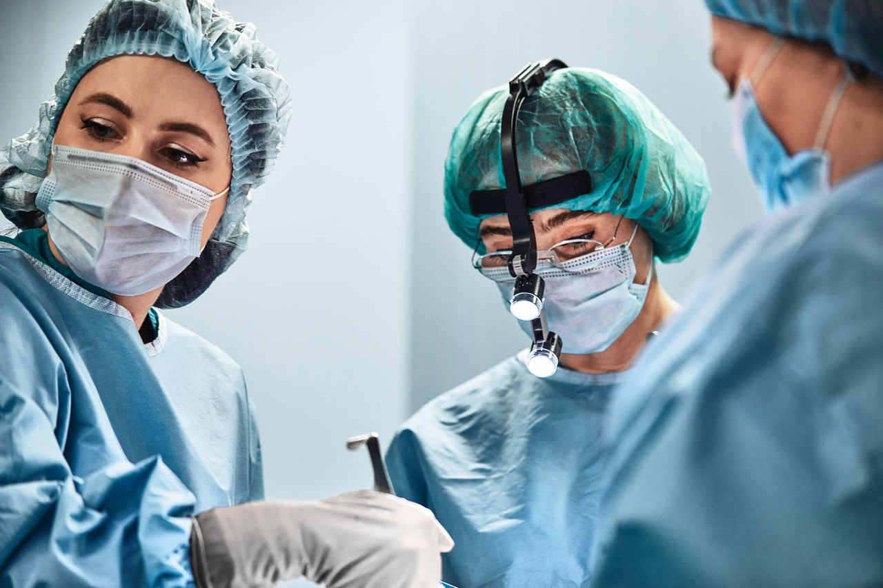 A surgeon s team in uniform performs an operation on a patient in the clinic of the center.,A surgeon s team in uniform performs an operation on a patient i